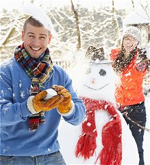 Adults playing in snow with snowman