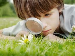 Young boy looking through magnifying glass trusting in synchronicity to teach what is needed  